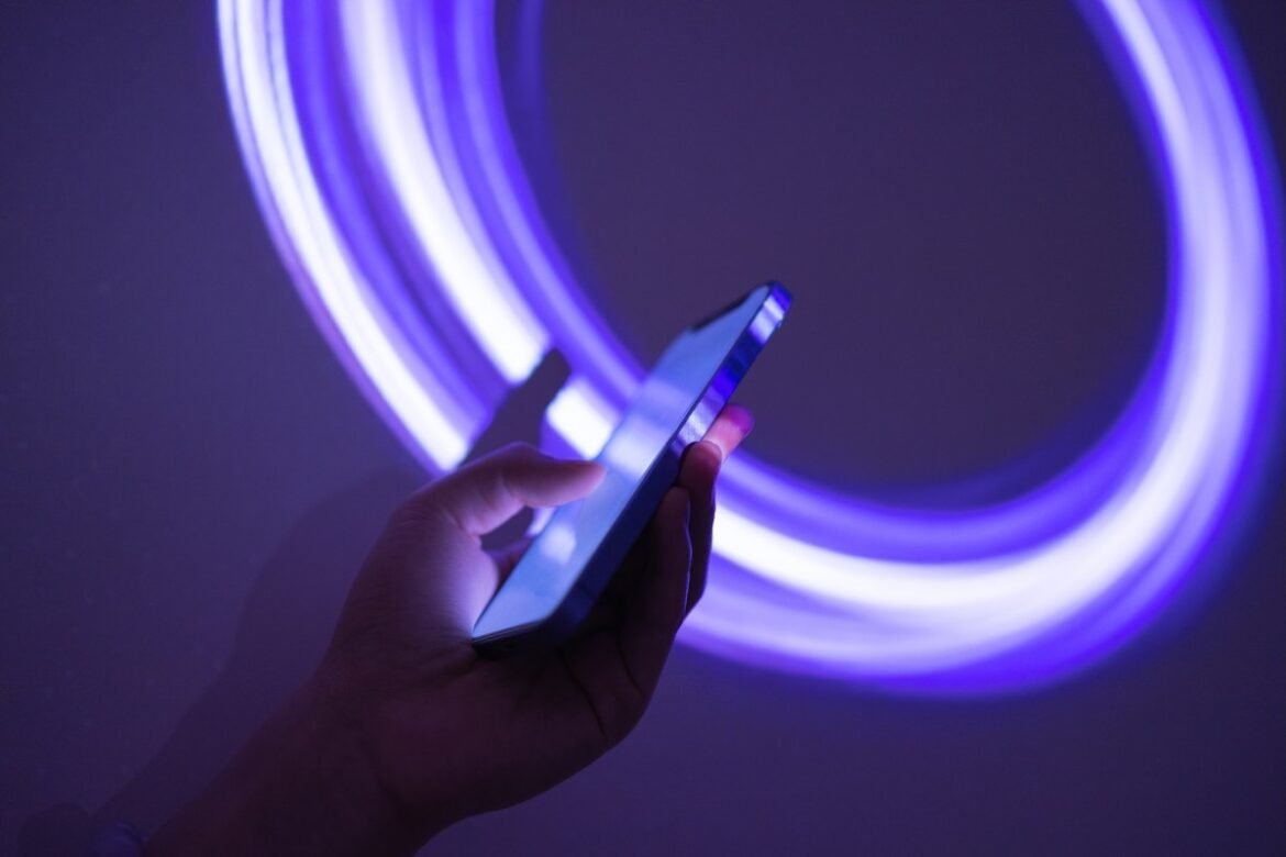 someone holding a phone on a neon purple background