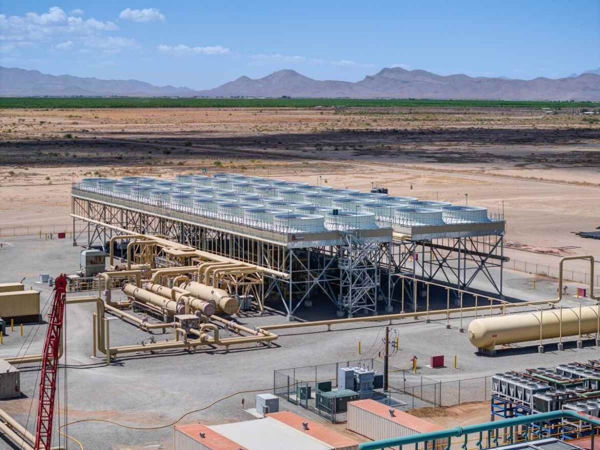 A geothermal power plant sits in front of a mountain range.